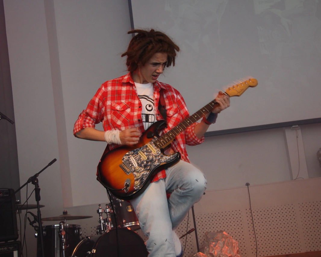 A guitarist seated with an electric guitar